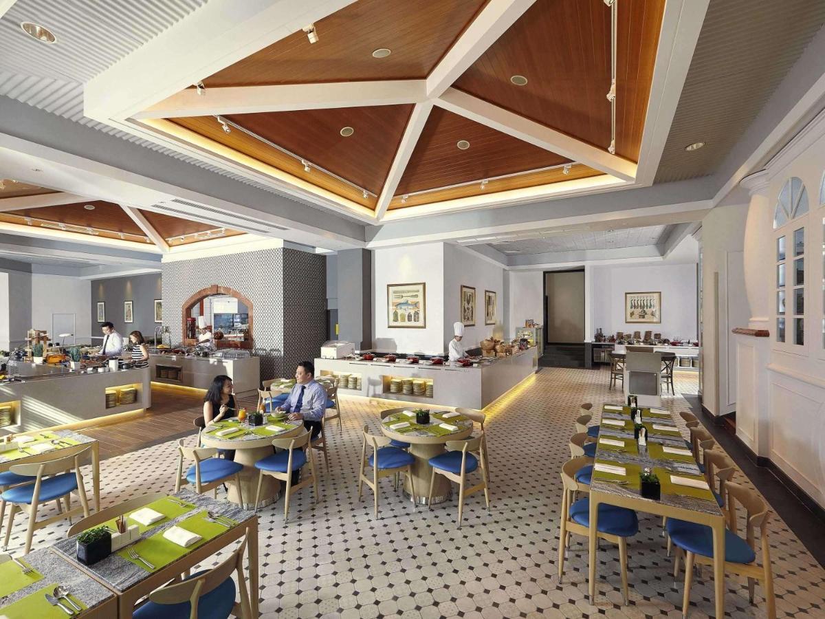 Paradox Singapore Merchant Court At Clarke Quay Екстериор снимка The photo depicts a modern restaurant interior. The space features a stylish design with a high ceiling and wooden details, creating an inviting atmosphere. 

Tables are neatly arranged, each set with green placemats and blue chairs. There is a secti