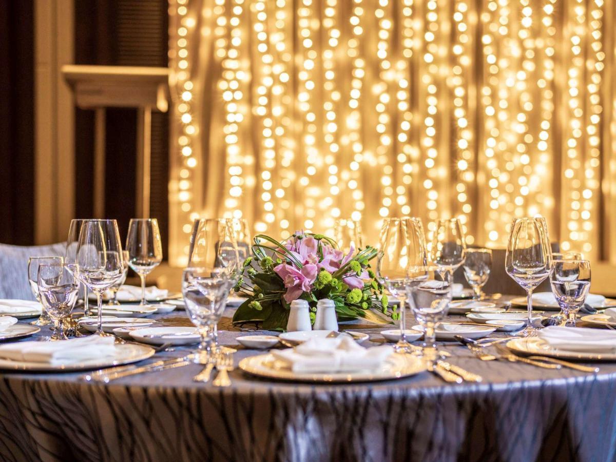 Paradox Singapore Merchant Court At Clarke Quay Екстериор снимка The image shows a beautifully set dining table, elegantly arranged for a special event or celebration. The table is covered with a stylish cloth, and there are several plates, glasses, and utensils neatly placed around it. In the center, there's a fl