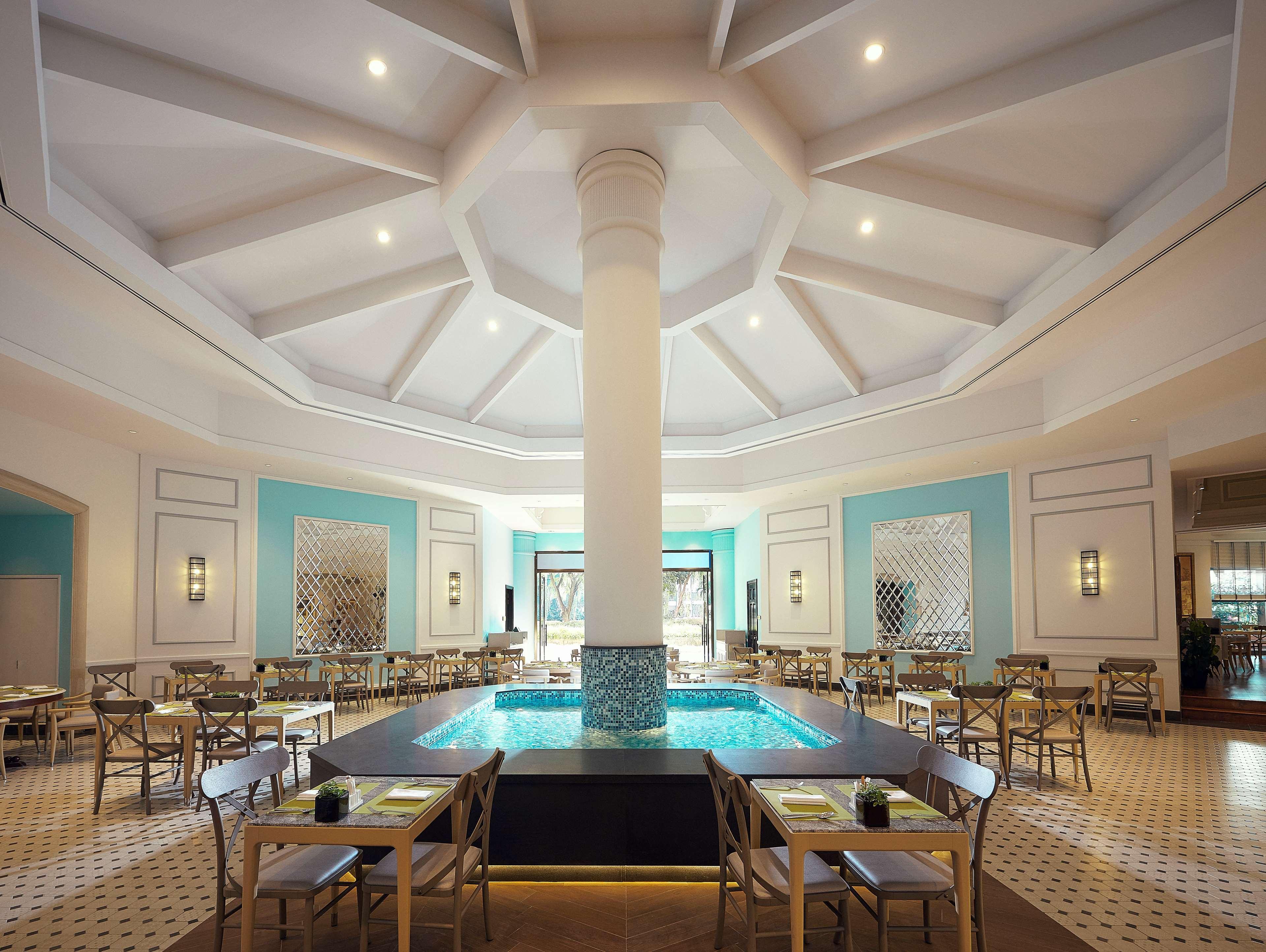 Paradox Singapore Merchant Court At Clarke Quay Екстериор снимка The photo shows an elegant dining area with a spacious, open layout. There is a large column in the center, surrounded by a circular water feature that adds a serene atmosphere. The ceiling is designed with a geometric pattern, giving it a modern loo