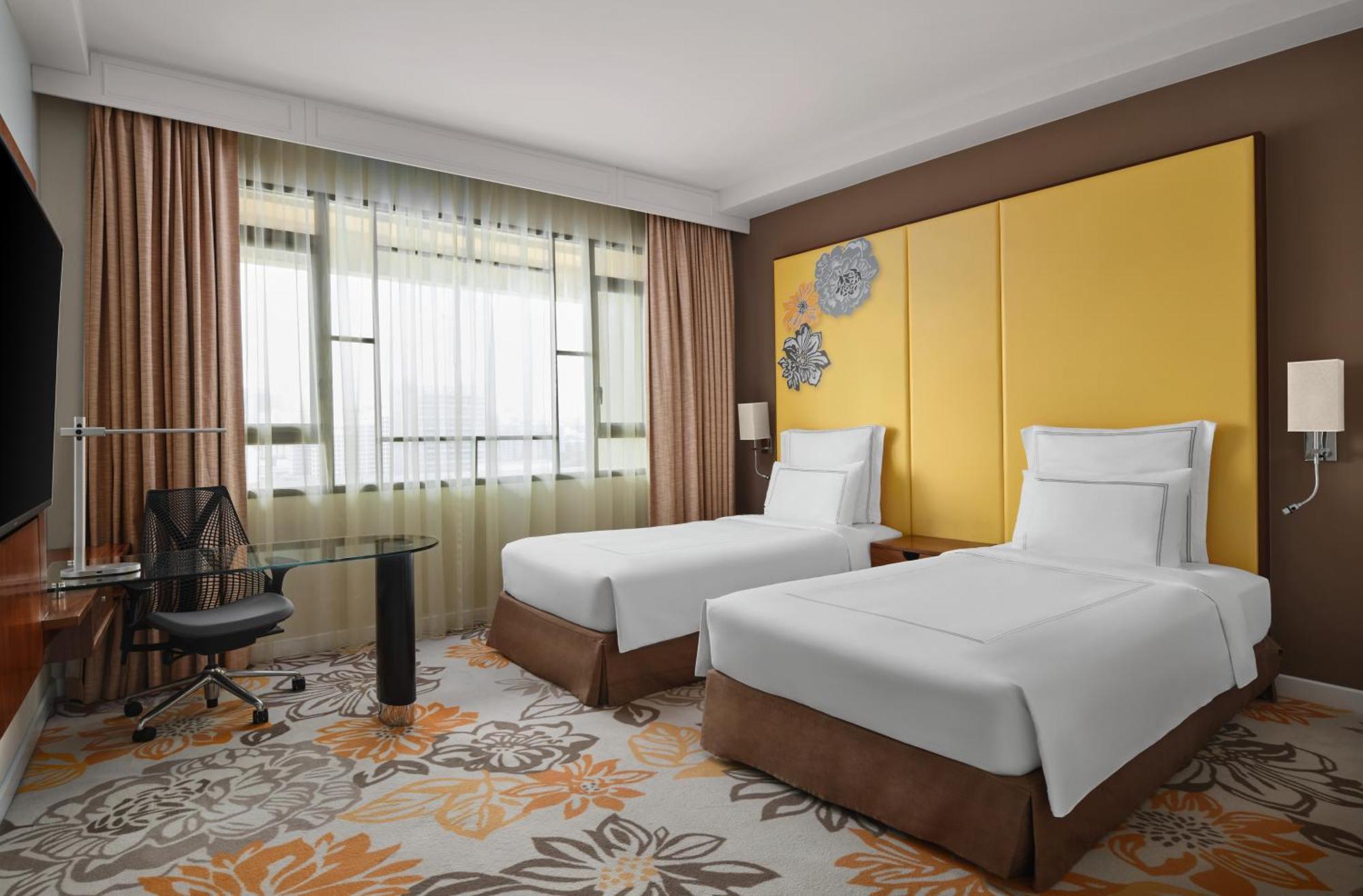 Paradox Singapore Merchant Court At Clarke Quay Екстериор снимка The photo shows a hotel room featuring two single beds with white linens and brown bed skirts. The room has a modern design with large windows dressed in sheer curtains, allowing natural light to enter. There is a small glass desk and an ergonomic ch